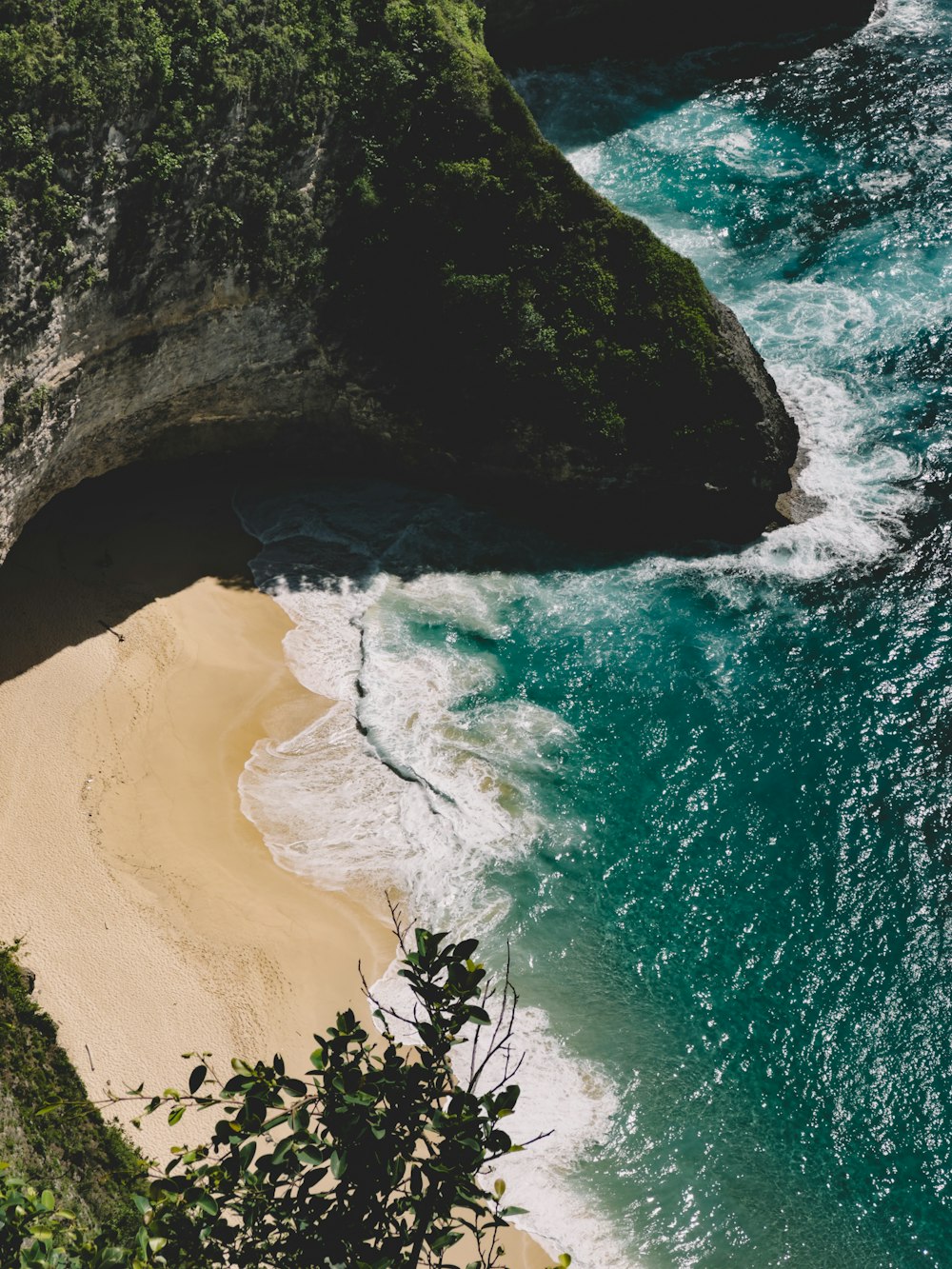 an aerial view of a sandy beach with a cliff in the background