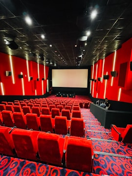a theater with red chairs and a projector screen