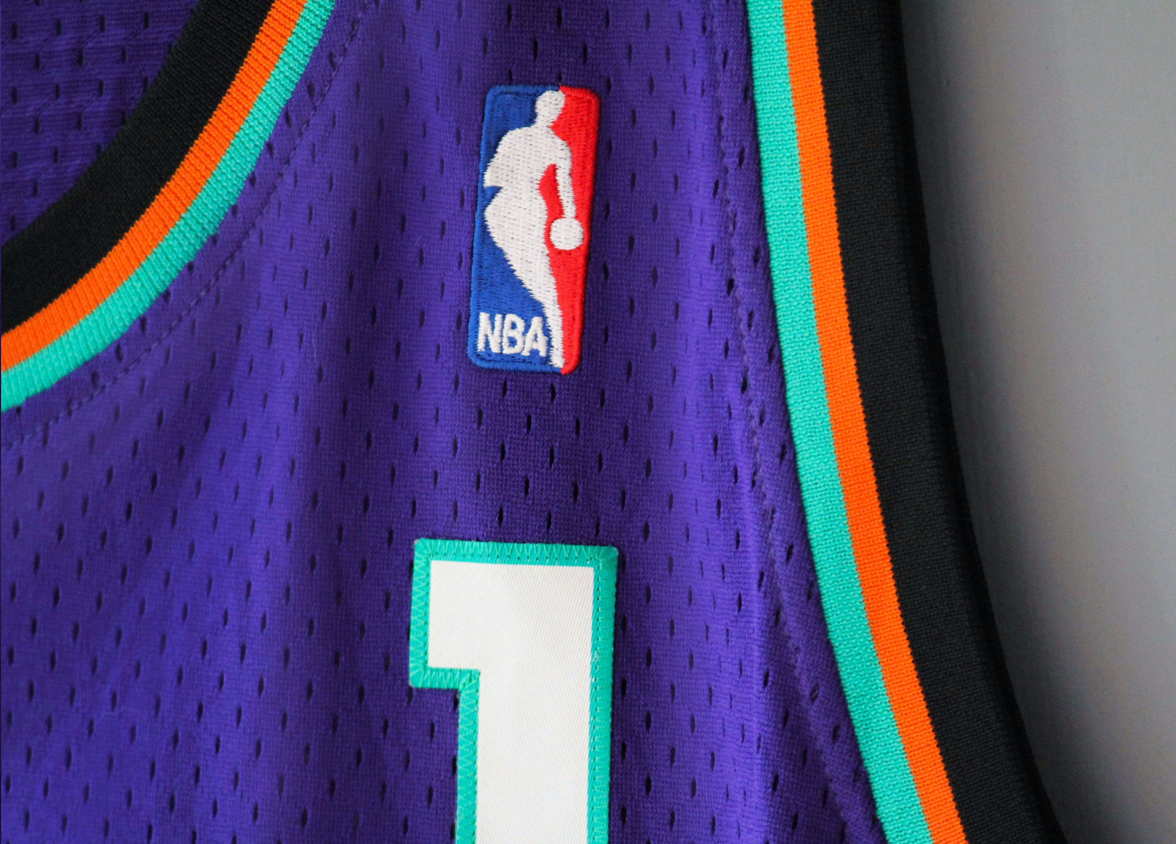 NBA logo on a blue/purple NBA Adidas Soul Swingman East all star Penny Hardaway basketball jersey with teal and orange trims. Photo by Abhay Siby Mathew. Travel back to the 1995 NBA All-Star Game in Phoenix, where the jerseys rocked shades of purple, orange, bright teal, and black. These jerseys weren’t just about style; they were a tribute to the city’s vibe. Inspired by the Suns’ colors-purple, black, and orange-the designs also borrowed patterns from the Navajo culture, adding a cool twist to the game’s look. So, those 1995 jerseys weren’t just uniforms; they were a celebration of basketball’s connection to the vibrant tapestry of Phoenix’s culture and history. Photo by Abhay Siby Mathew.
