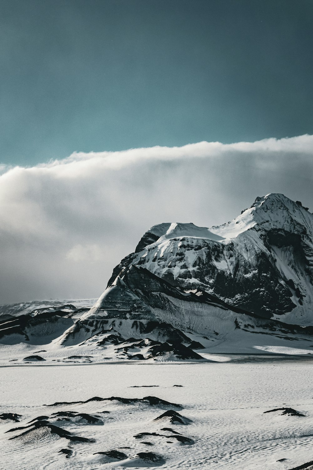 a mountain covered in snow under a cloudy sky