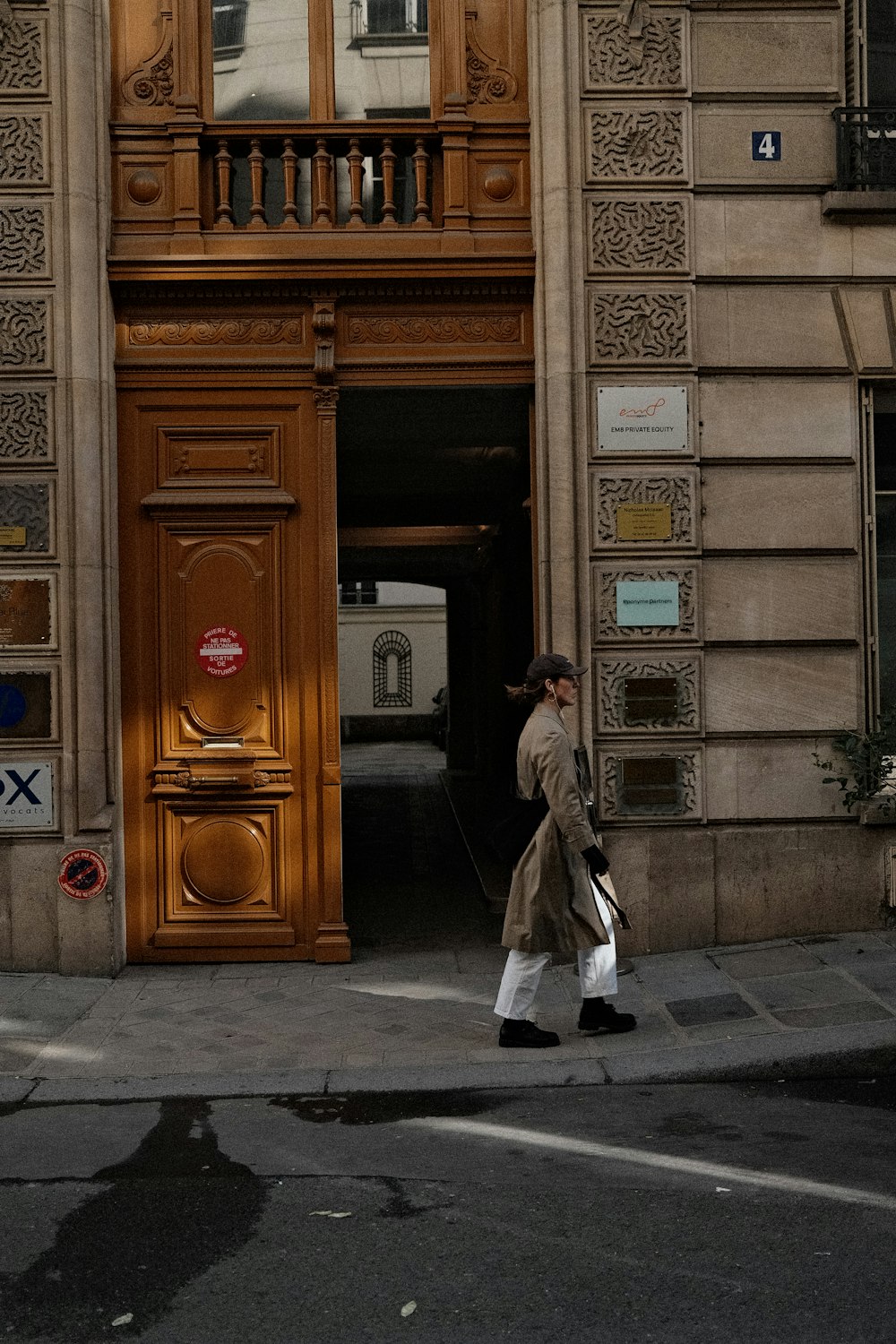 a woman walking down a street past a tall building