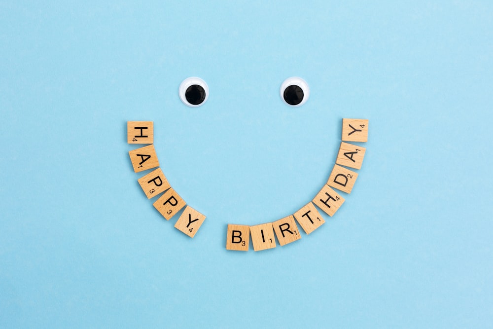 a smiley face made out of scrabbles with the words happy birthday spelled