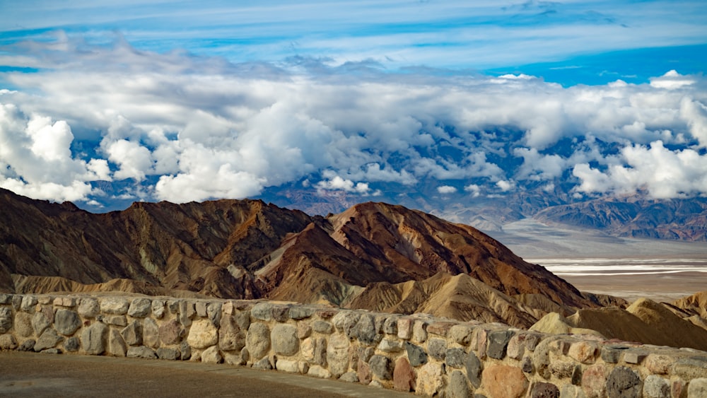 a stone wall in front of a mountain range