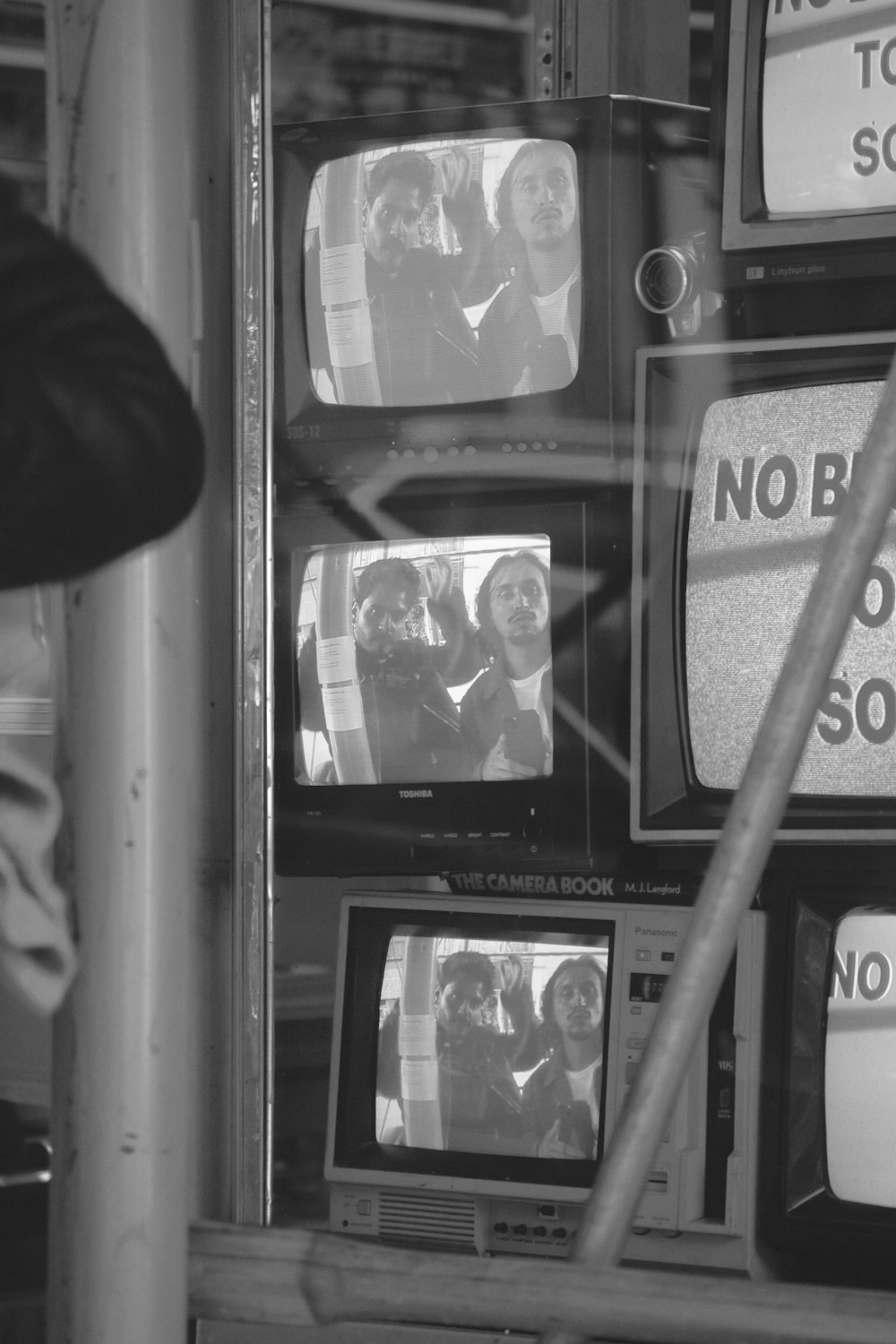 a black and white photo of tvs in a store window