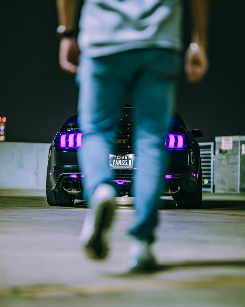 a man walking past a car with a purple tail light