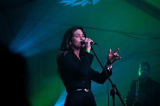a woman singing into a microphone on stage