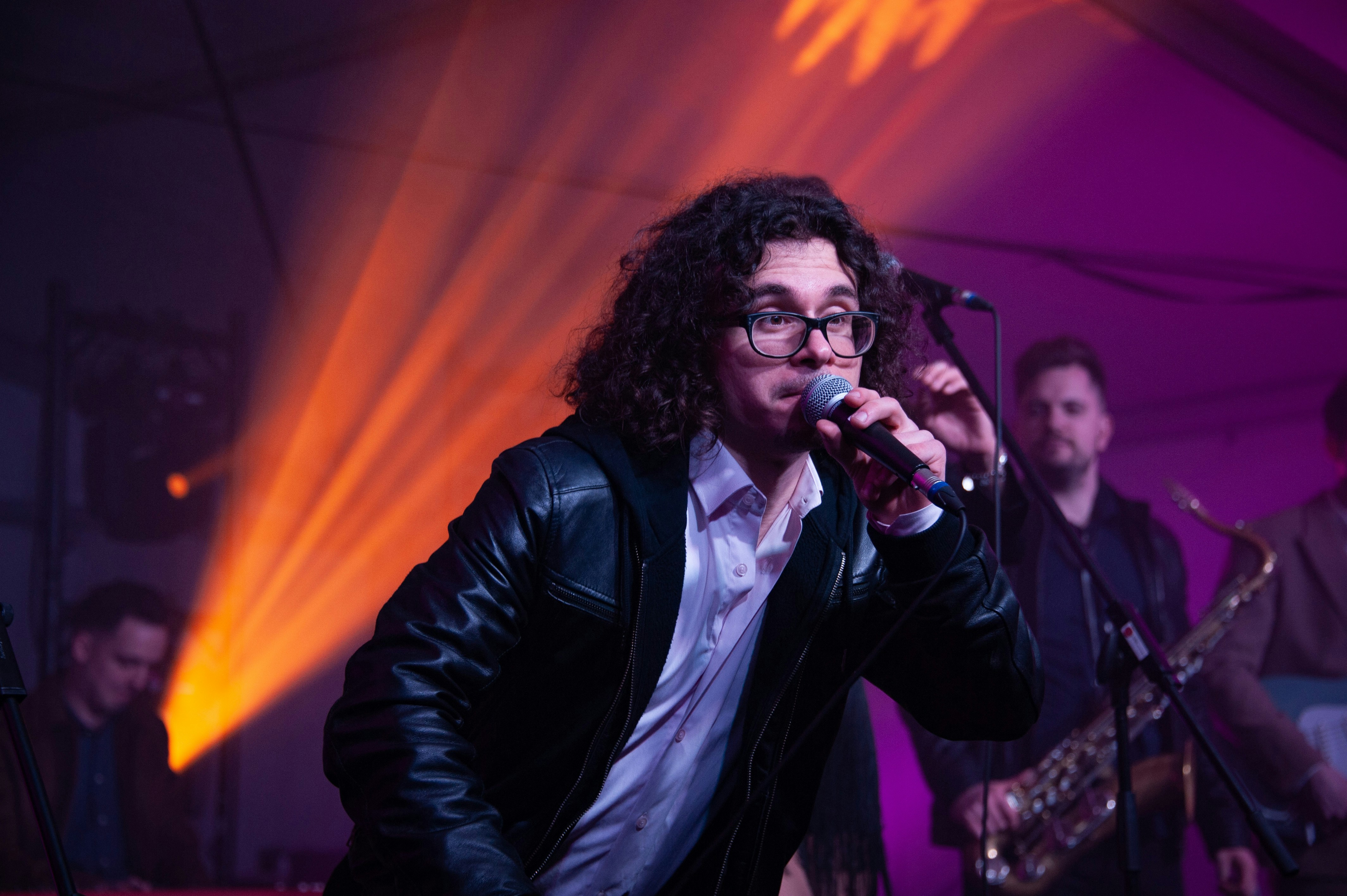 a man singing into a microphone in front of a band