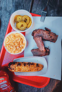 a tray of food that includes corn, macaroni and cheese