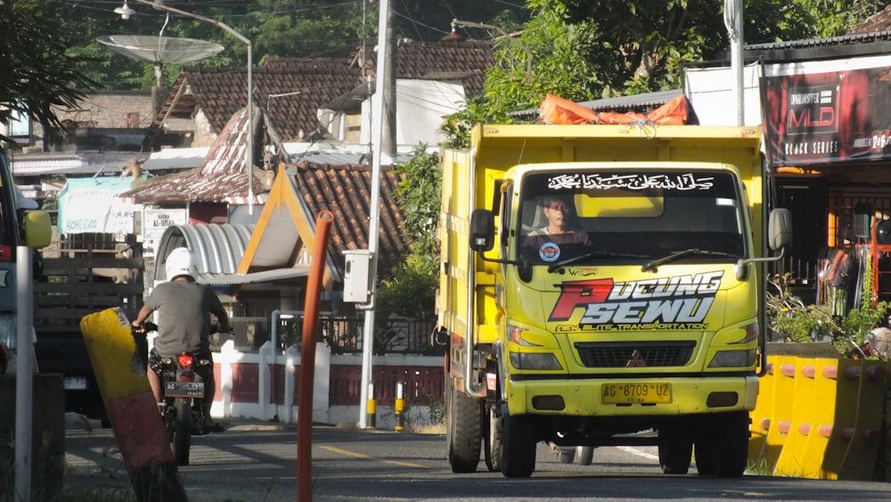a yellow truck driving down a street next to tall buildings