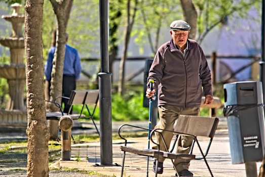 a man walking down a sidewalk next to a park bench