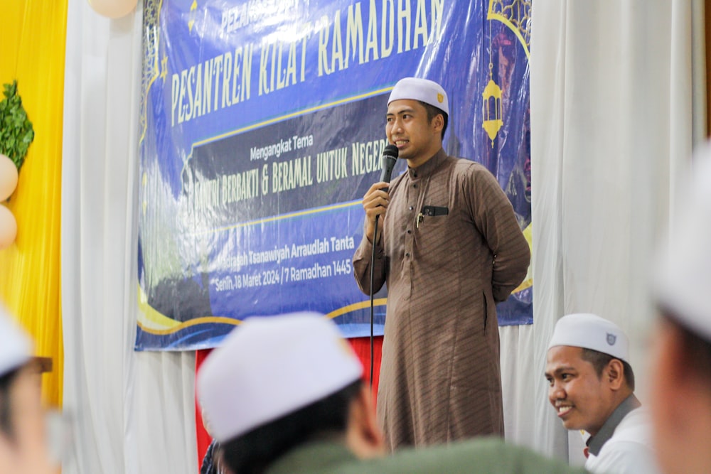 a man speaking into a microphone in front of a group of people