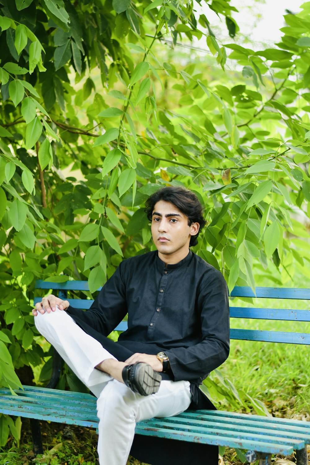 a man sitting on a bench in front of a tree