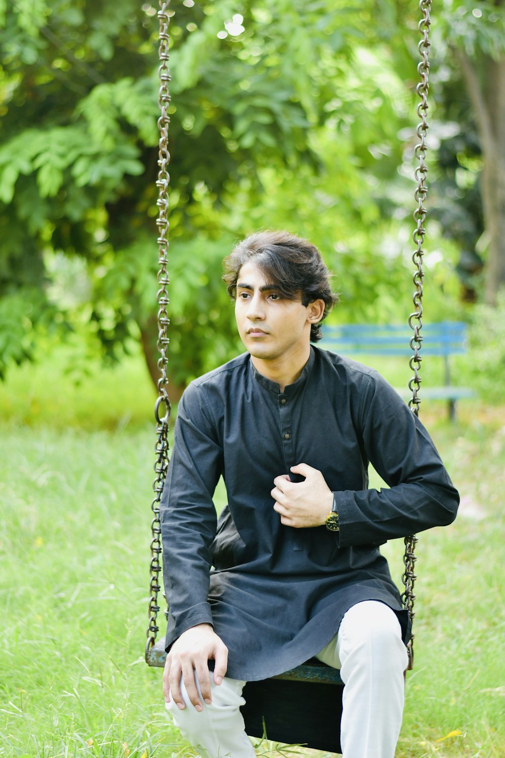 a man sitting on a swing in the grass