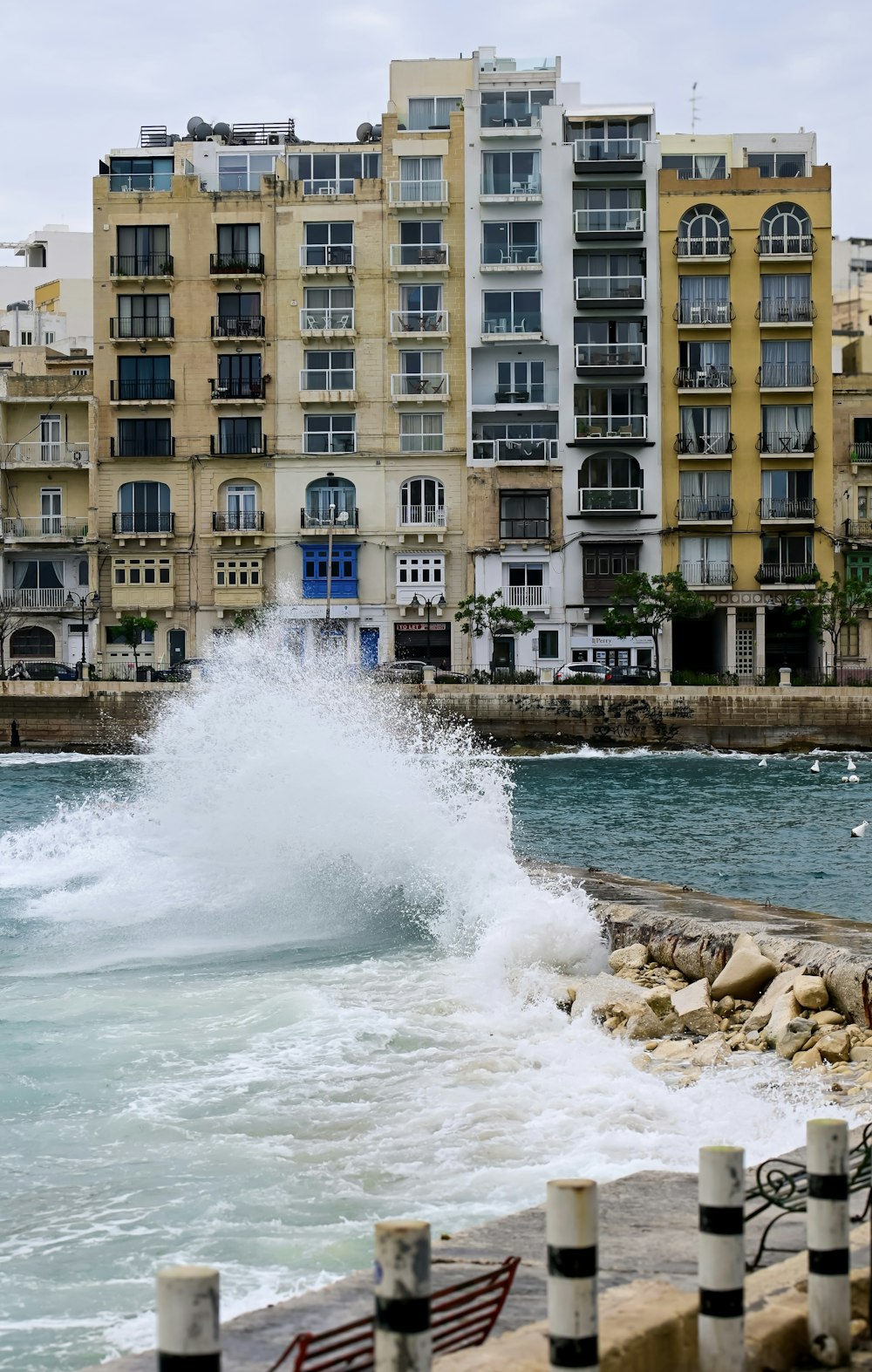 a large wave crashing into the ocean next to a city