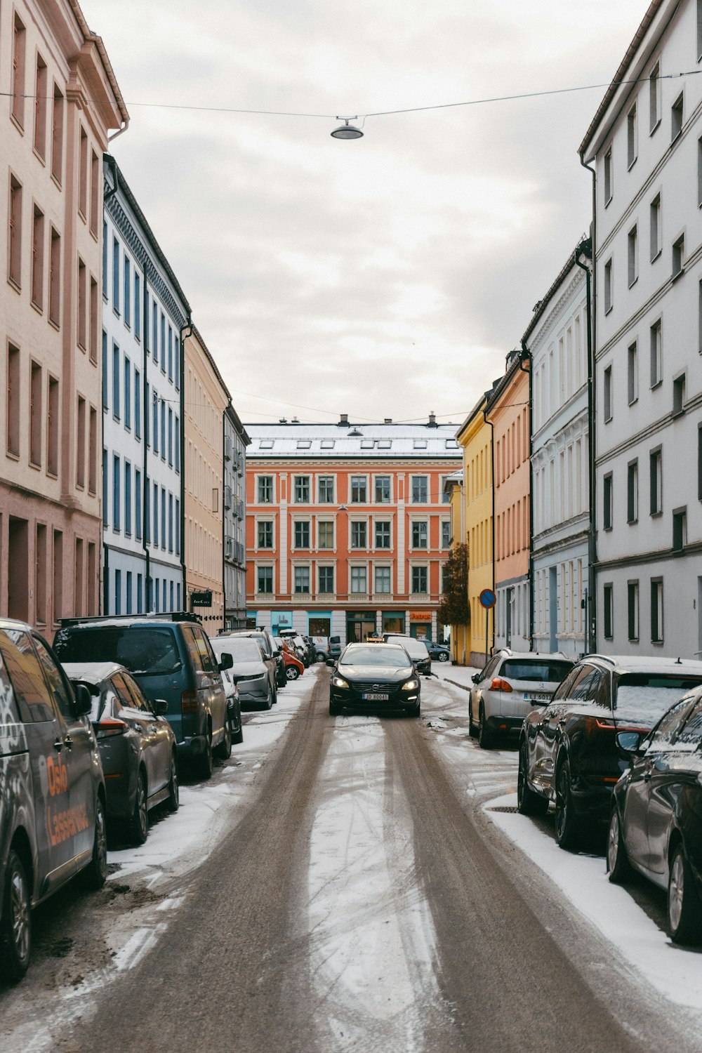 a street filled with lots of parked cars next to tall buildings