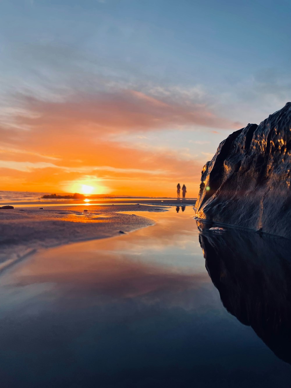 a couple of people standing on top of a beach