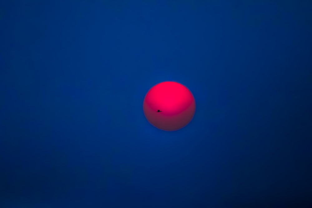 a red ball in the middle of a blue sky