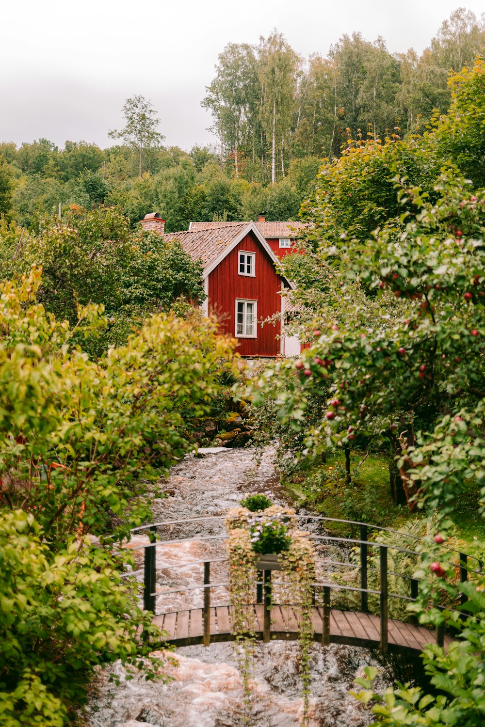 a red house surrounded by trees and a bridge