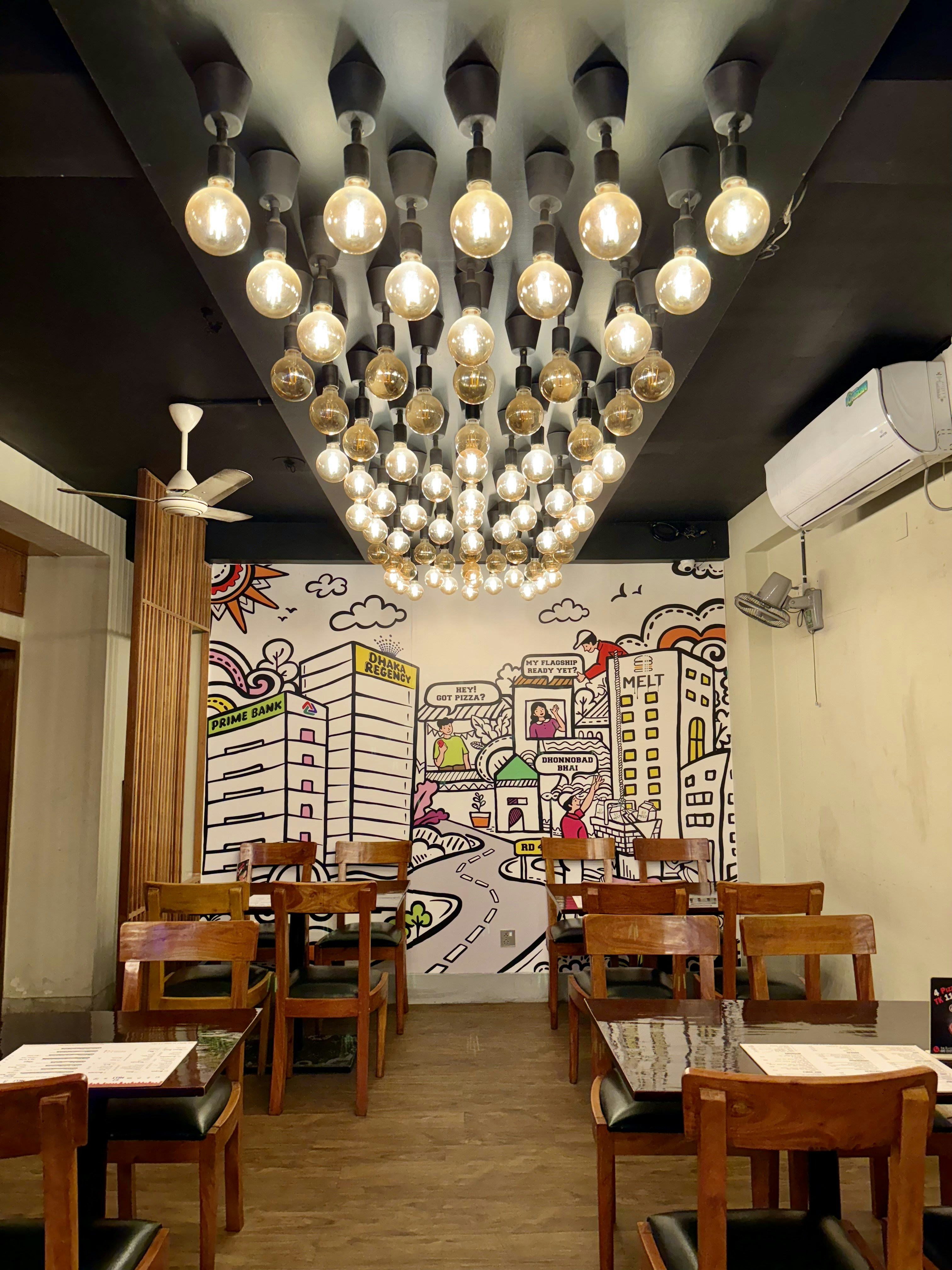 Elegant restaurant dining room with warm Edison bulb lighting, wooden tables, white tablecloths, soft amber glow