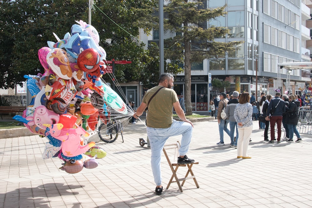 a man standing on a stool in front of a bunch of balloons