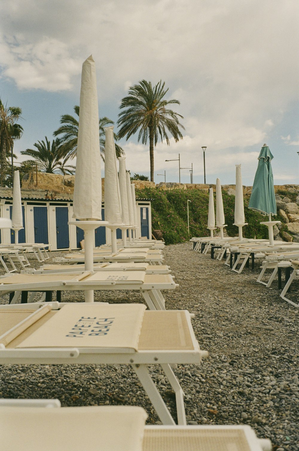 eine Reihe von Liegestühlen, die auf einem kiesbedeckten Strand sitzen