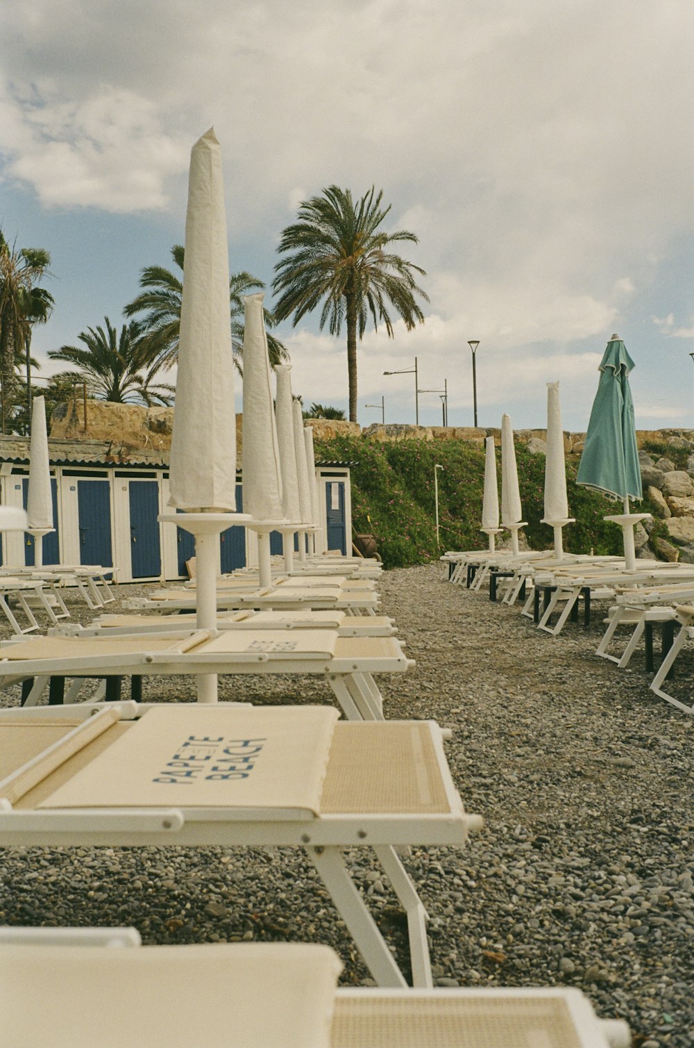 a row of beach chairs sitting on top of a gravel covered beach