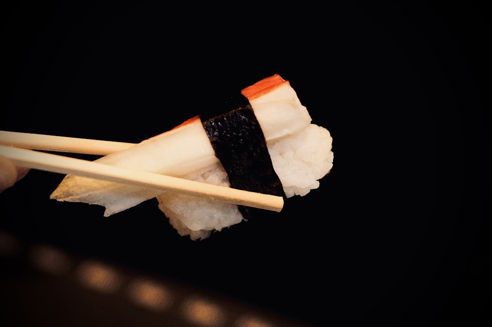 um pedaço de sushi com pauzinhos saindo dele