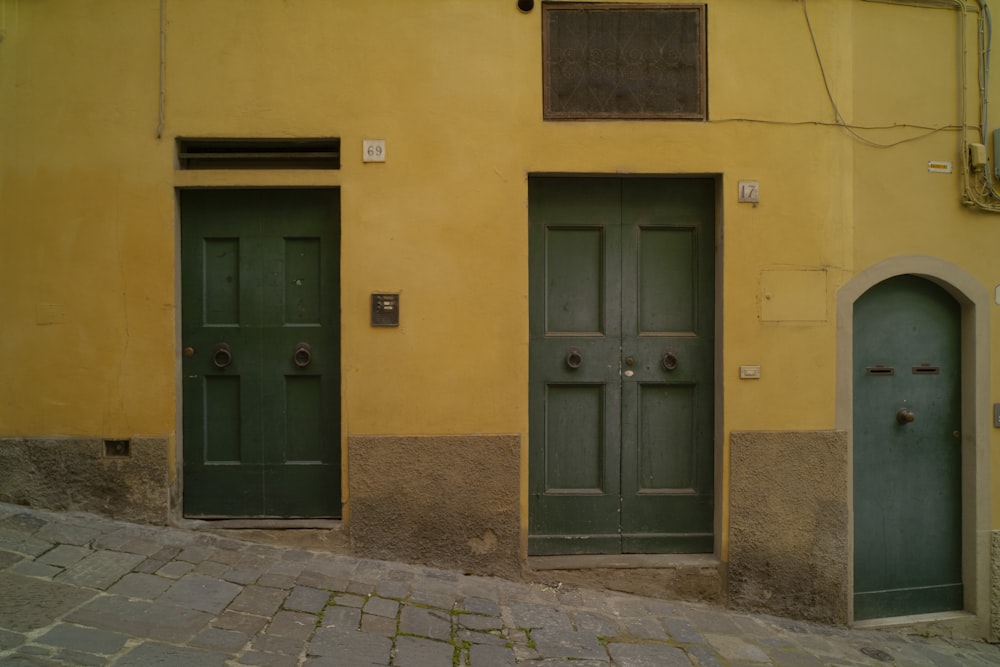 a couple of green doors on a yellow building