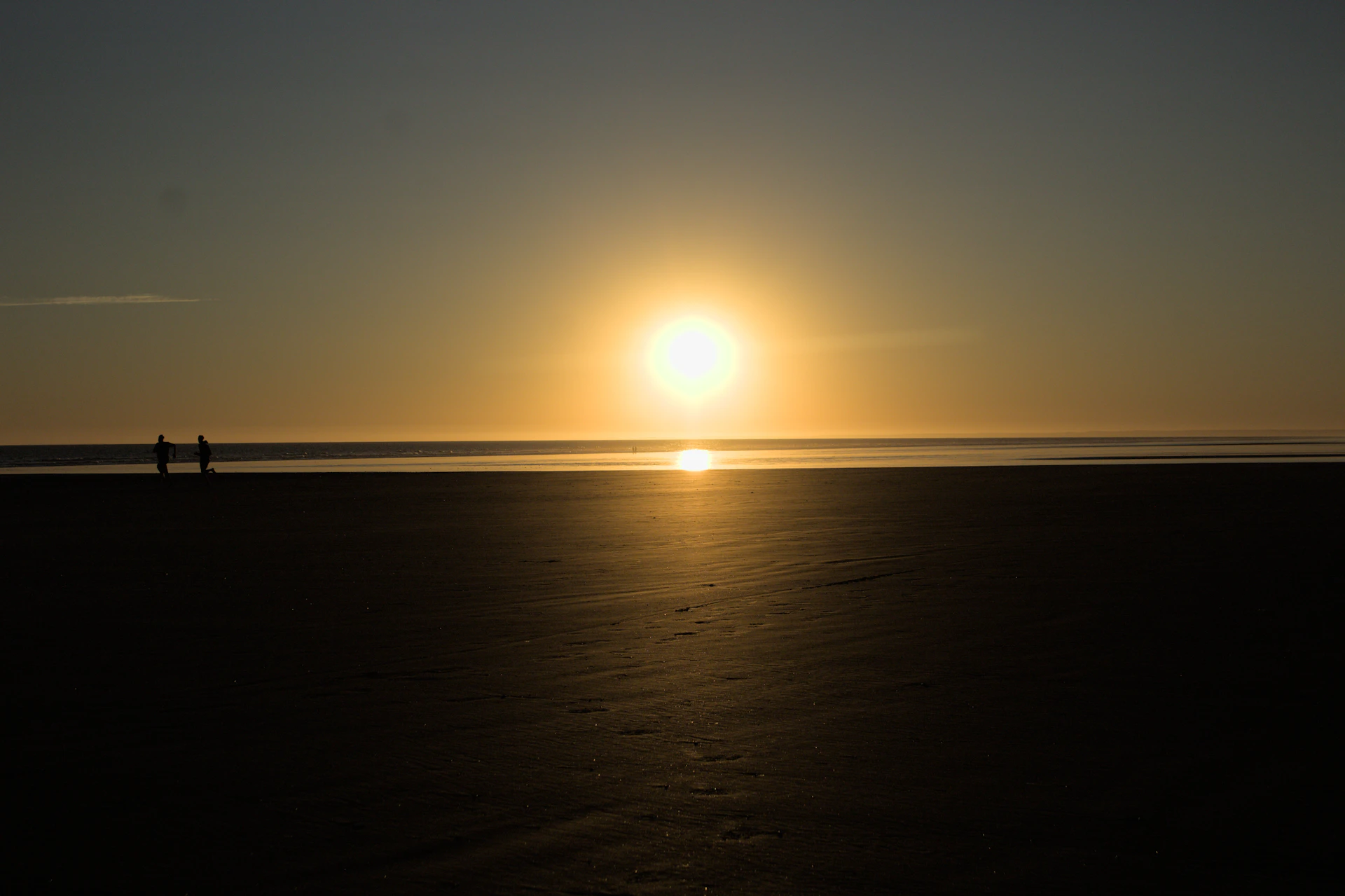 the sun is setting over the ocean on the beach