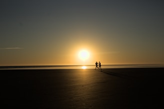 a couple of people standing on top of a beach