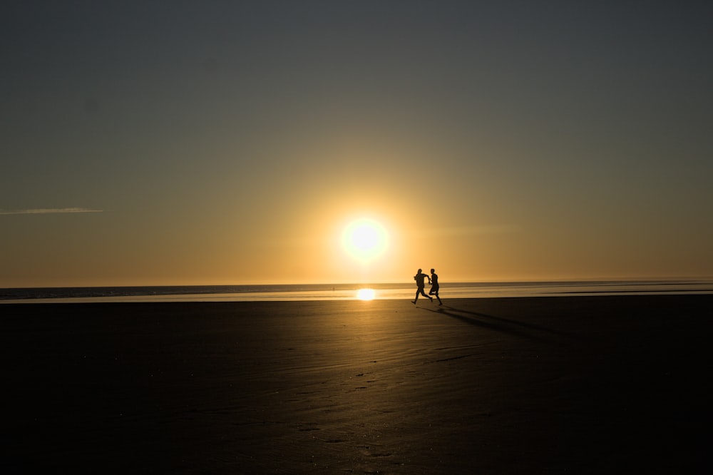 a couple of people standing on top of a beach