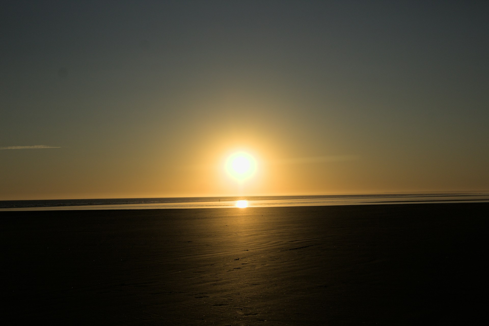 the sun is setting over the ocean on the beach