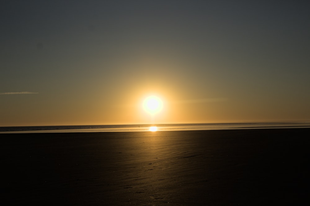 the sun is setting over the ocean on the beach