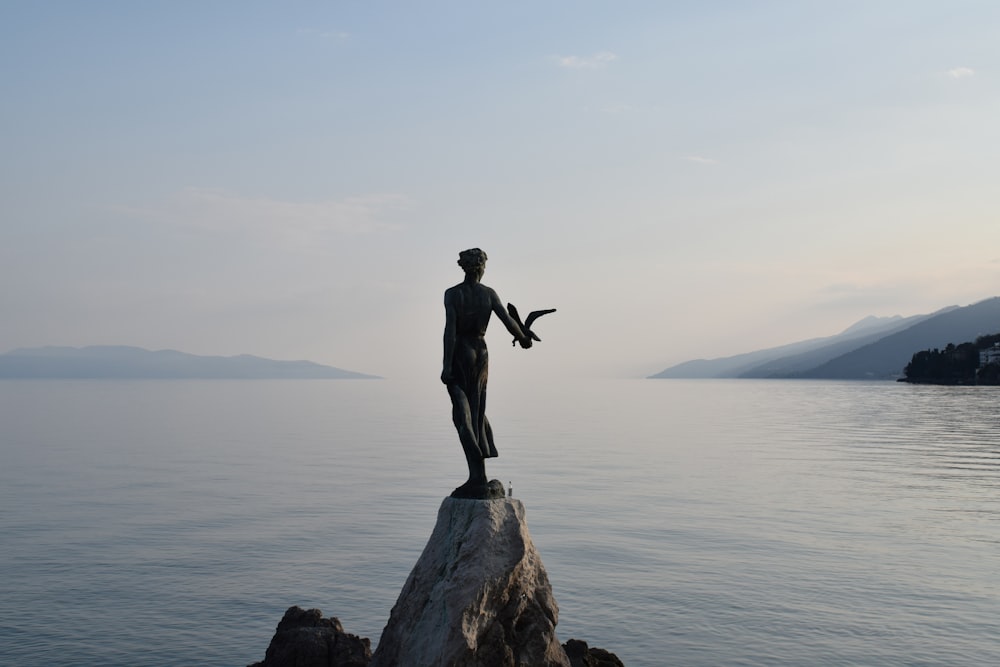 una statua di un uomo in piedi sulla cima di una roccia