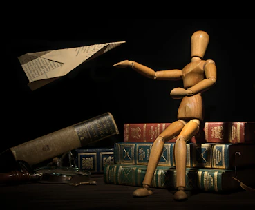 a wooden doll sitting on top of a pile of books
