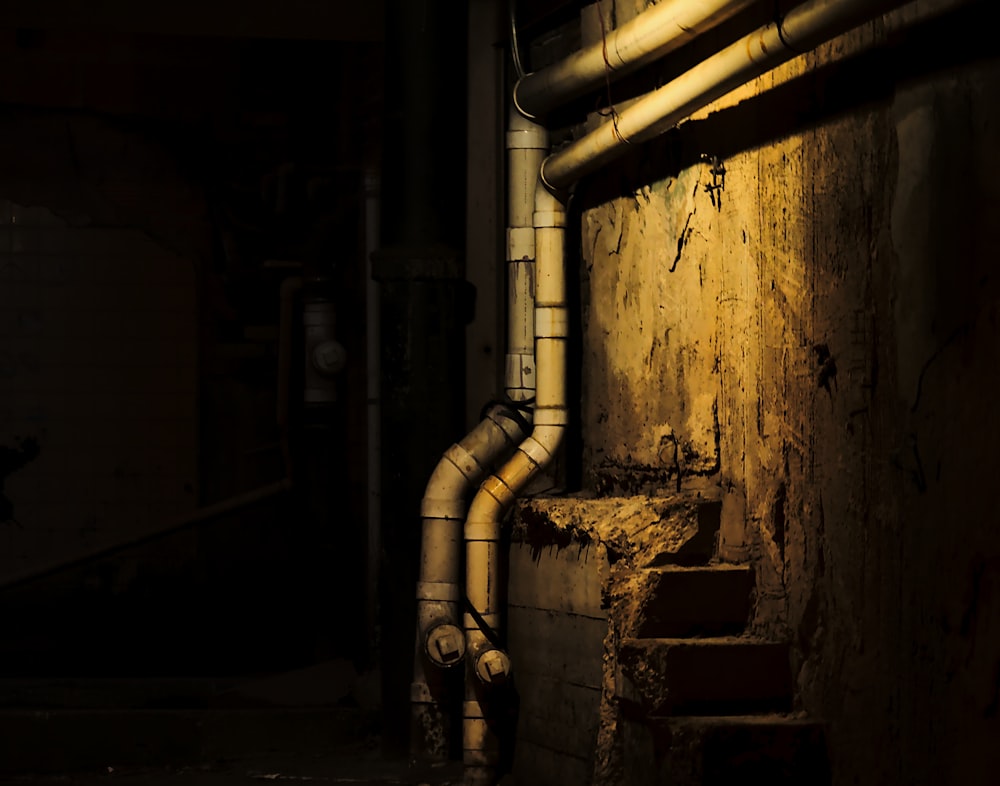 a dark room with pipes and a window