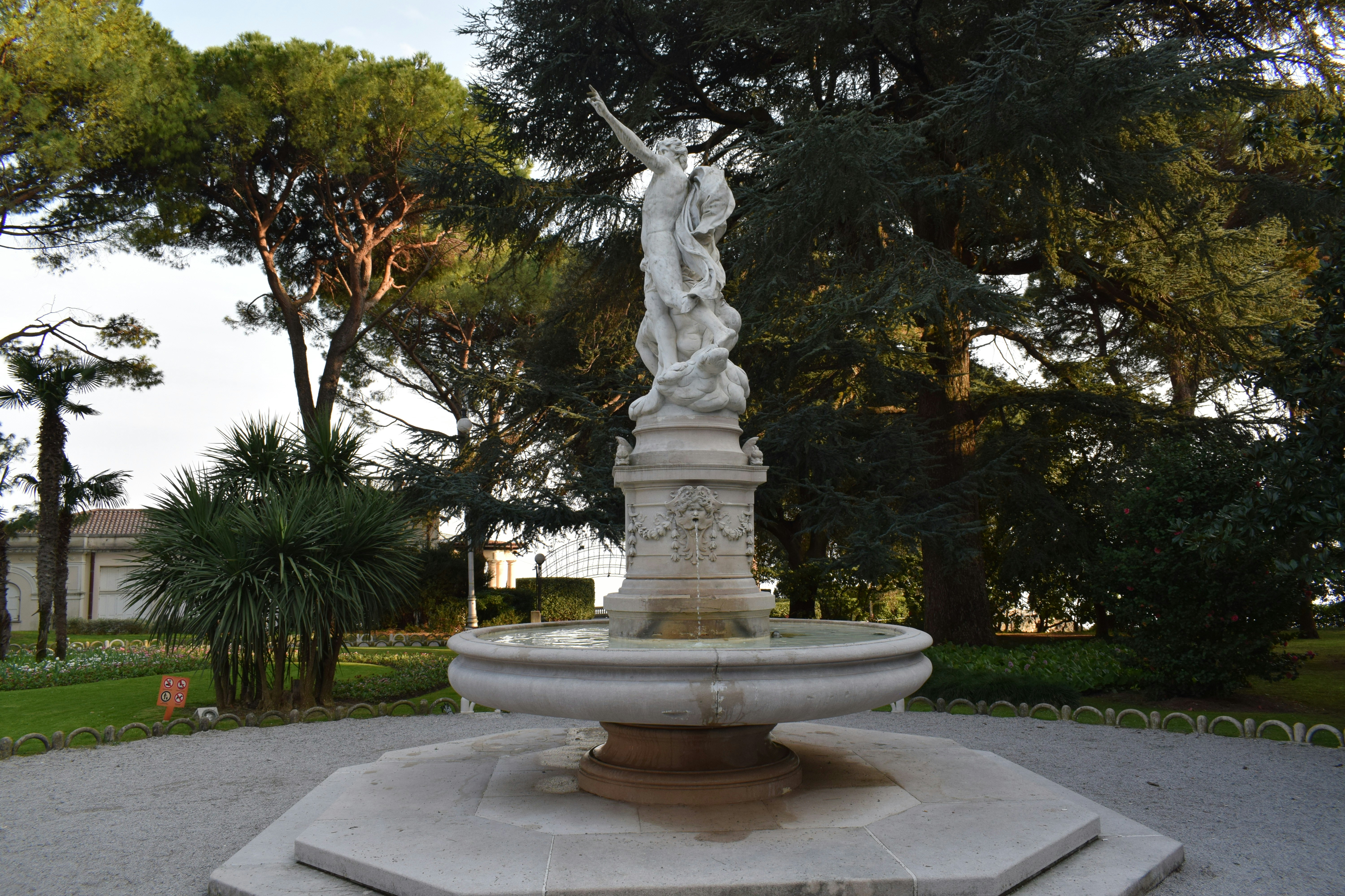 a statue in the middle of a park with trees in the background