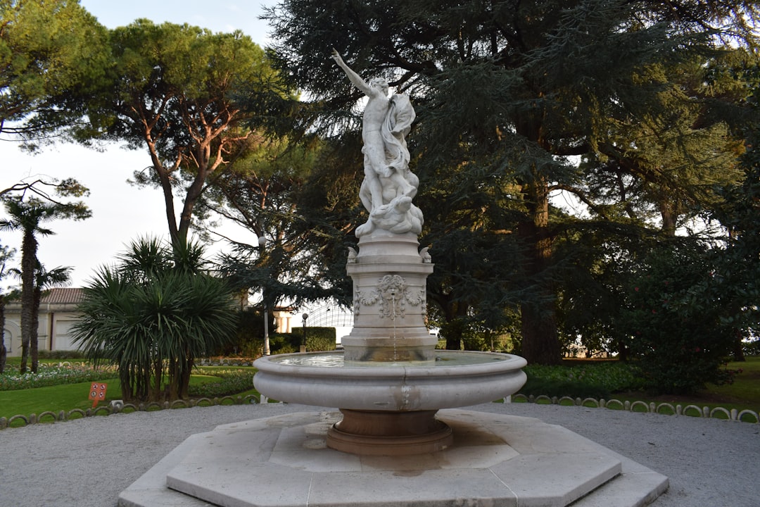 a statue in the middle of a park with trees in the background, Beautiful water fountain in Opatija.