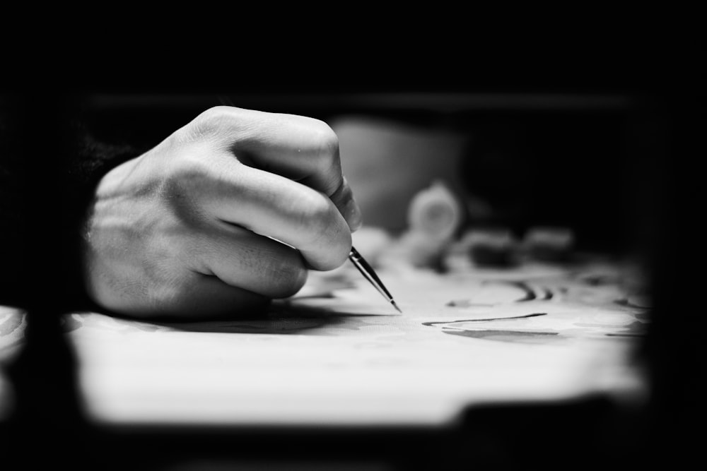 a person writing on a piece of paper with a pen