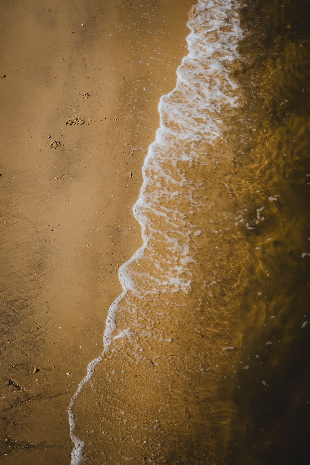 a sandy beach with waves coming in to shore