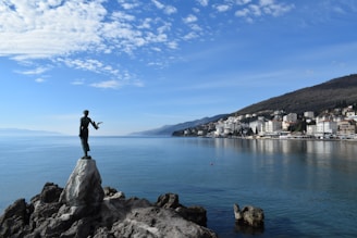 a man standing on top of a rock next to a body of water