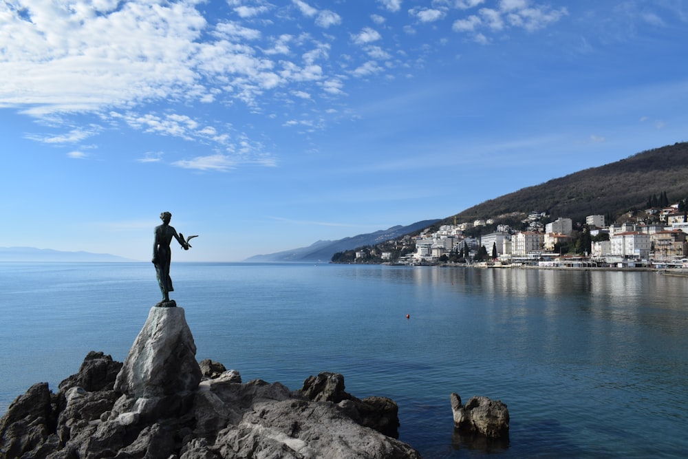 Un hombre parado en la cima de una roca junto a un cuerpo de agua