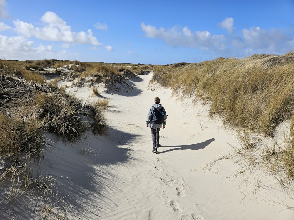 a person walking down a path in the sand