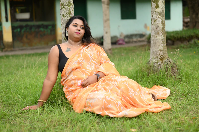 Indian sugar mama sitting gracefully on the grass in a sari