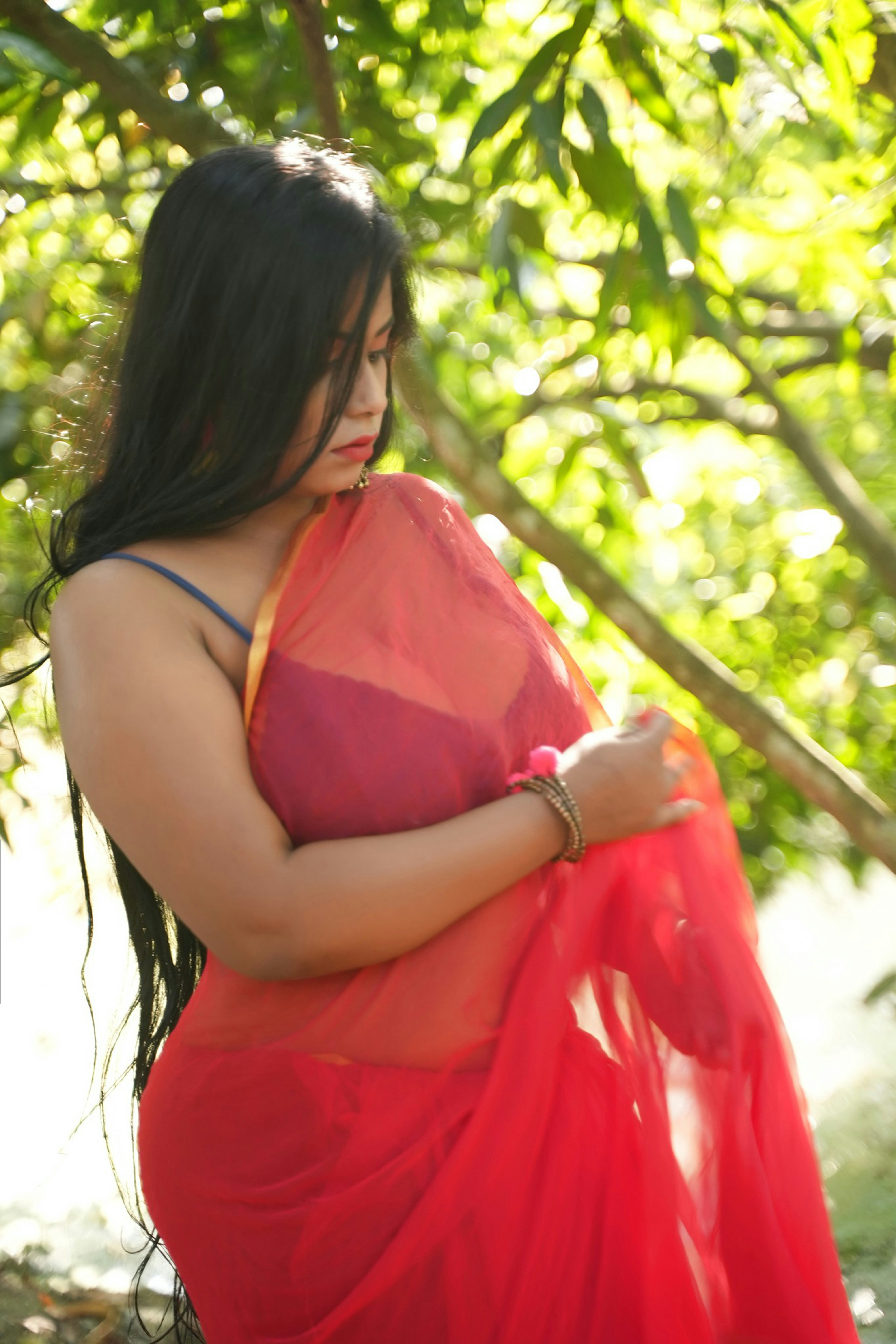 a woman in a red dress standing under a tree
