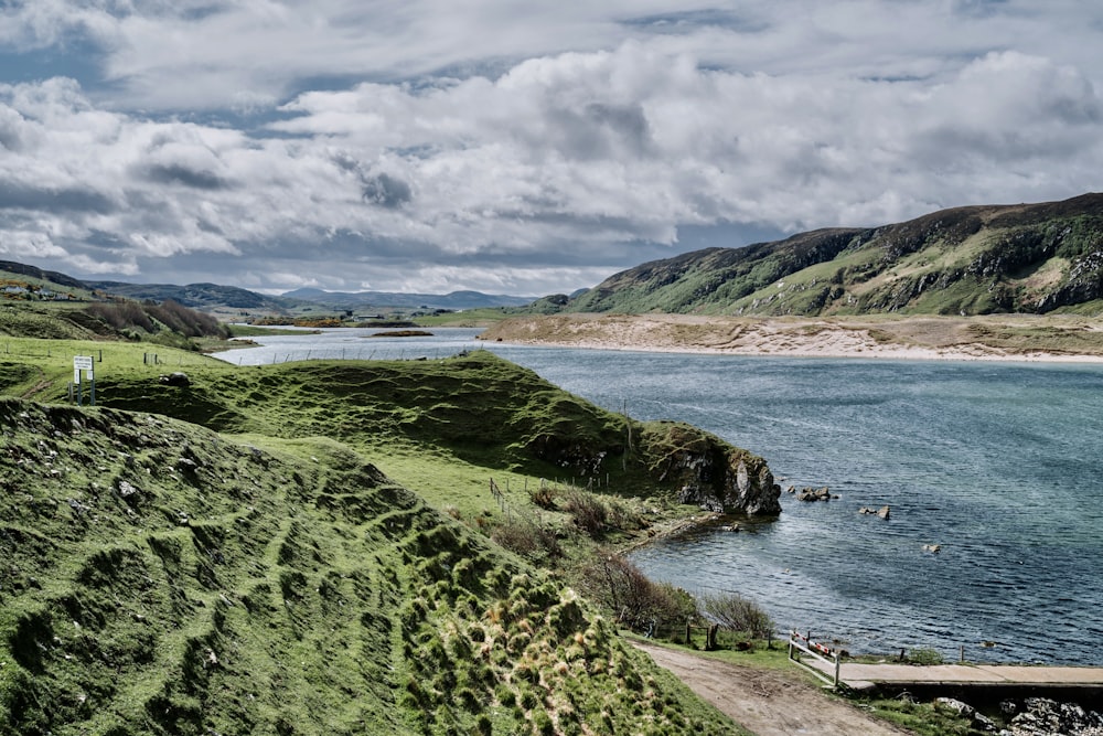 a body of water surrounded by green hills