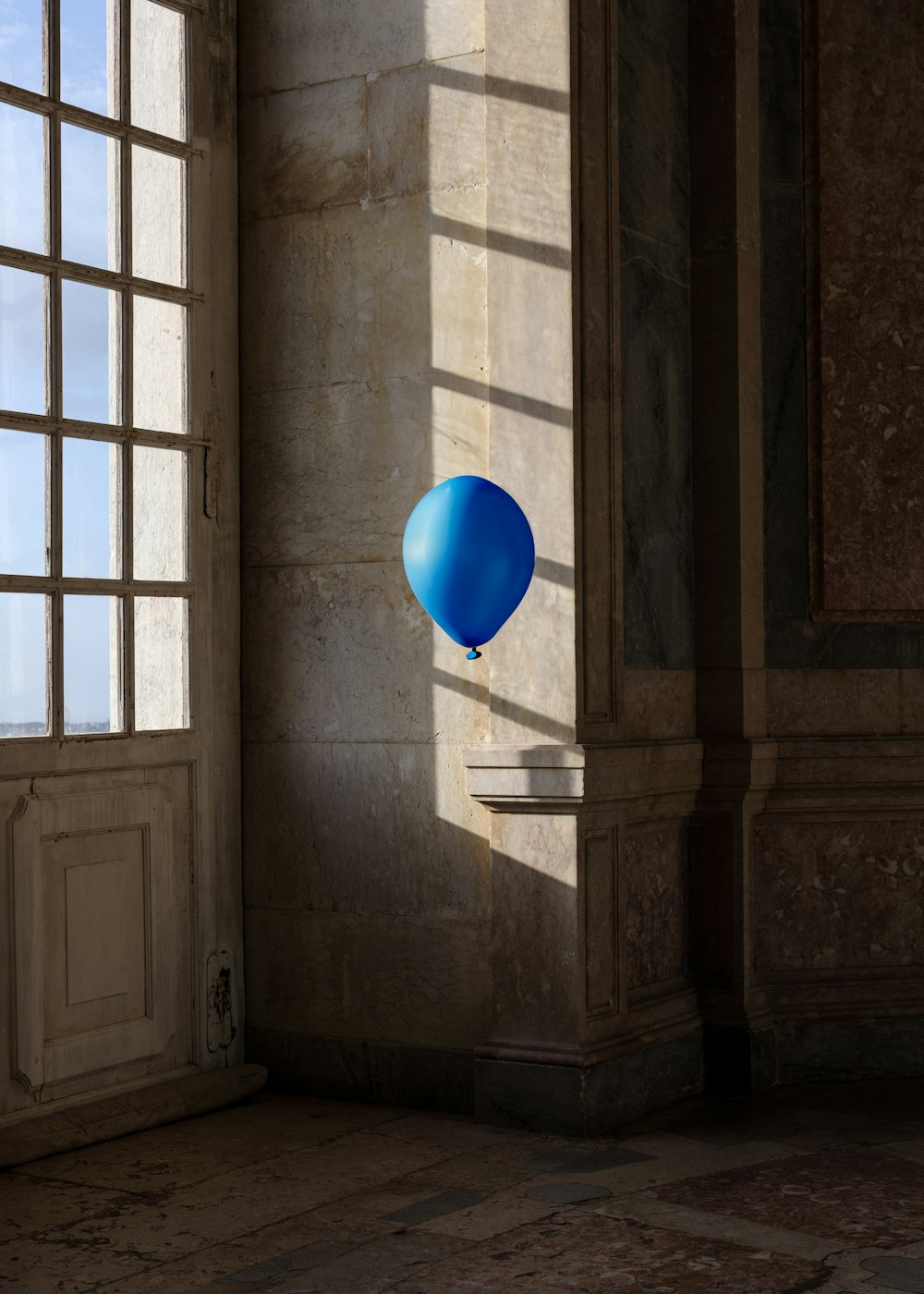 ein blauer Luftballon, der neben einem Fenster in der Luft schwebt