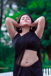 a woman in a black sari poses for a picture