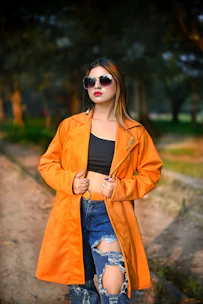 a woman in an orange jacket and ripped jeans