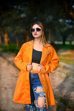 a woman in an orange jacket and ripped jeans